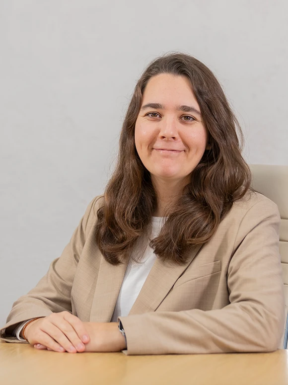 The image shows a smiling woman with long, dark hair, wearing a beige jacket and seated at a desk, as indicated by the filename "Belen Duran Web"