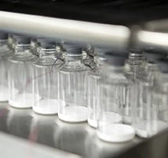 A row of clear glass containers or vessels in a laboratory or industrial setting, with the filename "lsne 3" suggesting a related identifier or label