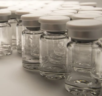 A collection of clear glass bottles with white screw-top lids, arranged neatly on a surface