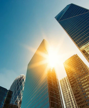 Towering glass skyscrapers with the sun shining brightly through, creating a captivating cityscape
