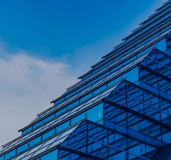 A modern glass and steel building with a distinctive angular design against a bright blue sky