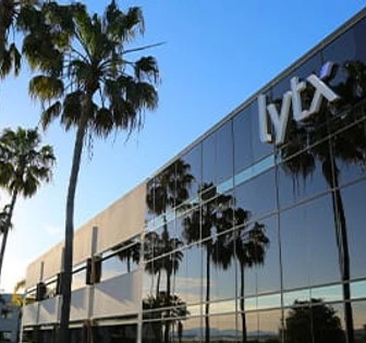 This image depicts a large, modern building with the "Lytx" logo prominently displayed on the front. The building is surrounded by palm trees, creating a scenic, tropical setting