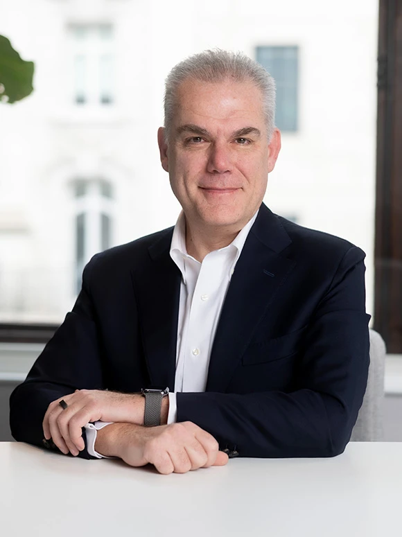 The image shows Roberto Biondi, a mature professional man with gray hair, wearing a suit and posing confidently in what appears to be an office or business setting