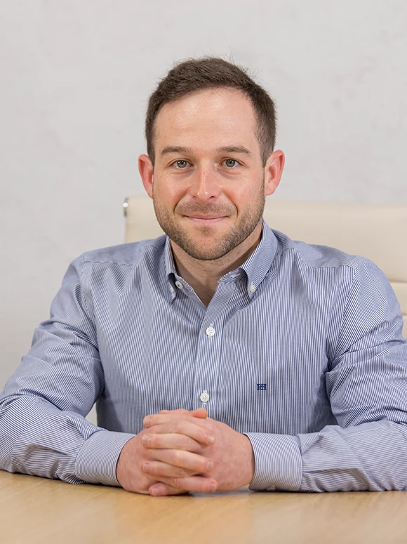 Pablo Sanchez, a smiling, well-dressed man, posing in a professional setting, with a friendly and approachable expression