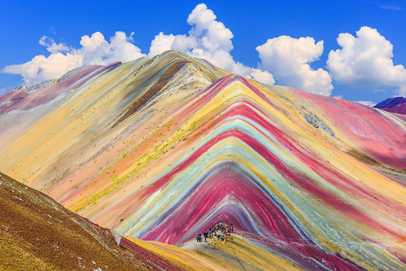 Rainbow mountains with people walking through them 