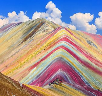 Rainbow mountains with people walking through them 