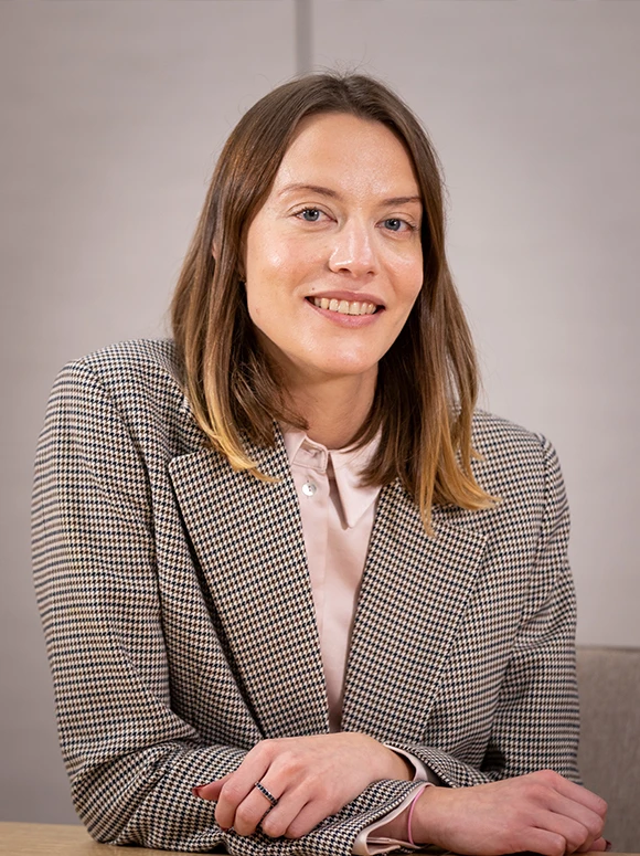 The image shows a middle-aged woman with long, brown hair wearing a checkered blazer, sitting at a desk and smiling warmly at the camera. The file name indicates this is a portrait of Silvia Payo