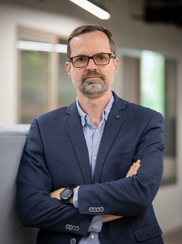 Joaquin Moraga Gallego, a man in business attire with a beard and glasses, standing in an office setting with a serious expression
