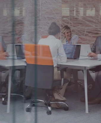 Four business people having a meeting in a modern office setting with computers and work materials on the desks