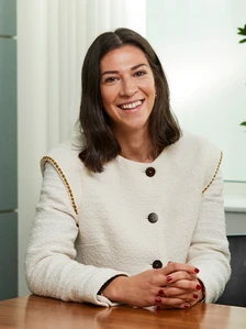 A smiling, professionally dressed woman with long dark hair, facing the camera and seated at a table, according to the image filename "Kate.Rossiter"