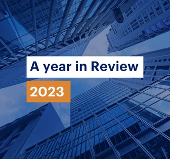 The image shows a collage of modern high-rise buildings and skyscrapers against a blue sky, with the text "A year in Review 2023" overlaid