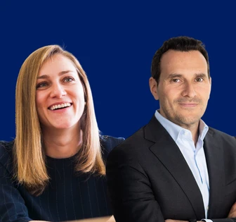 Ariadna and David H., a smiling business couple posing confidently against a blue background