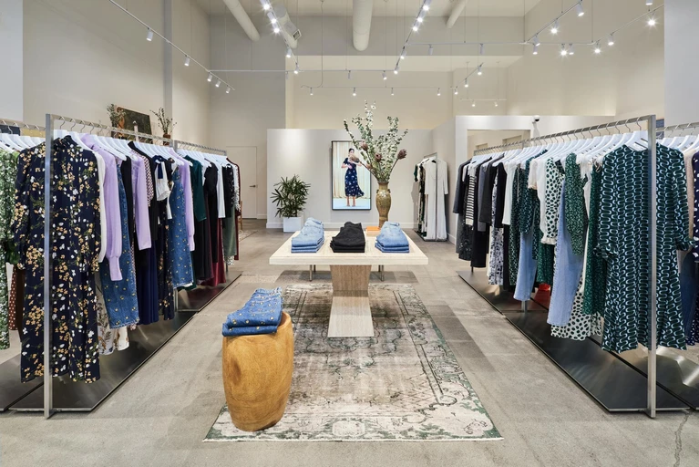 The image shows the interior of a Reformation clothing store in Portland, featuring neatly arranged racks of fashionable women's clothing, accessory displays, and an inviting, well-lit retail space
