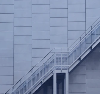 The image depicts a modern, angular building with a series of glass and steel structures extending outward, creating an intricate, geometric architectural design