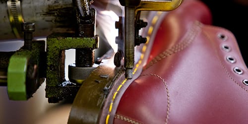 A red leather show being stitched.