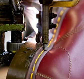 A red leather show being stitched.