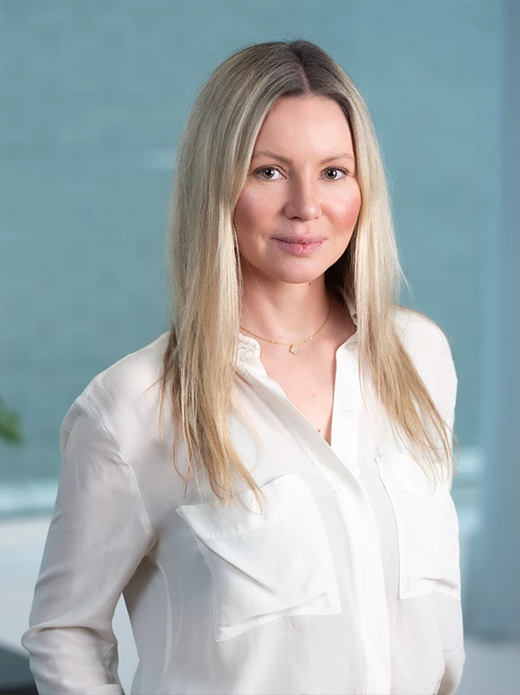 The image shows a professional portrait of Julia Reynolds, a woman with long, blonde hair wearing a white blouse against a light blue background