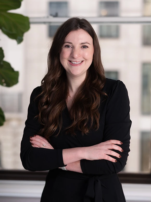 The image shows a smiling woman with long, dark hair wearing a black outfit, standing in front of a blurred background. The filename indicates her name is Lauren Beadle