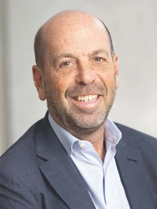 The image shows a smiling middle-aged man with a bald head and beard, wearing a blue suit and a light blue shirt. He appears to be an executive or professional, likely Jeff B based on the file name