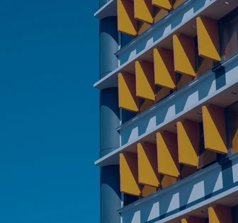 The image shows a colorful building facade with repeating geometric patterns of triangles in shades of yellow and blue