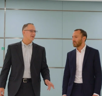 Two men in suits walking together, discussing a business partnership