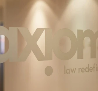 The image shows the Axiom law firm logo with the text "law redefined" displayed prominently on a wall or surface